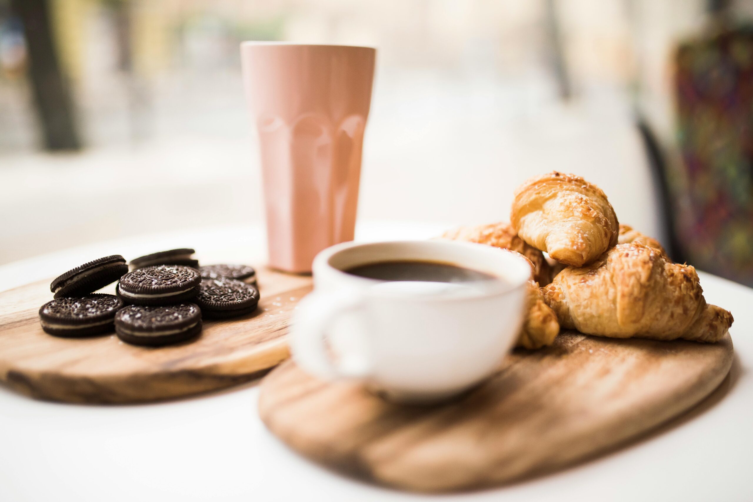 A cozy coffee break with a cup of coffee, cookies, and fresh croissants on wood platters.